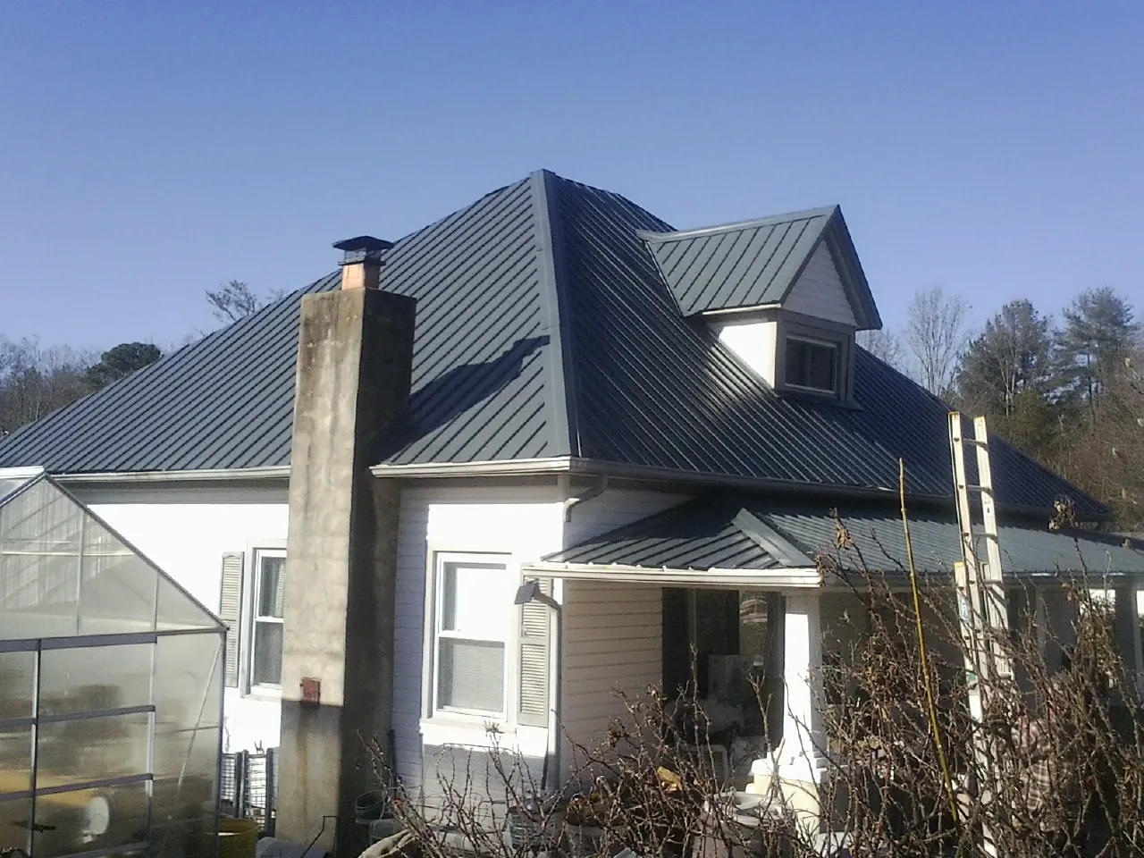 Dark blue standing seam metal roof on a white farmhouse with dormer — Slate & Tile Roof Repair by Roofing Brothers in Pricedale