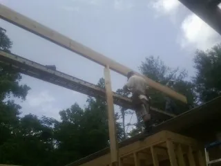 Carpenter setting a ridge beam over a new addition frame — Ice Dam Removal by Roofing Brothers in Pricedale