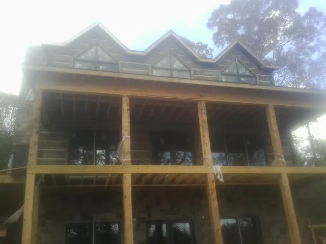 Dormers and porch framing on a large log home under construction — Roof Coating work by our crew in Pricedale