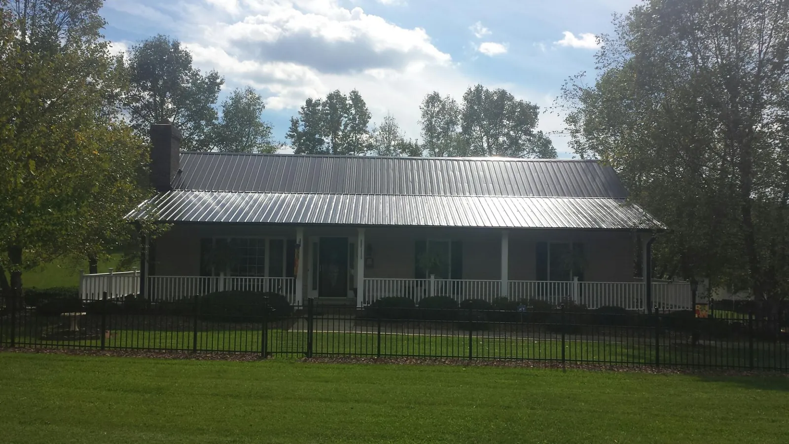 Gray metal roof on a brick ranch with a full width front porch — Gutter Guard Installation work by our crew in Pricedale