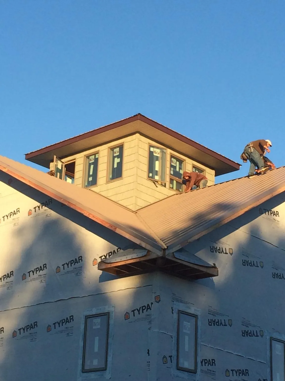 Roofers working around a rooftop cupola on a new metal roof at sunset — Roof Waterproofing in Pricedale by Roofing Brothers